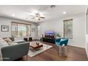 Bright living room featuring neutral walls, wood flooring, a ceiling fan, and large windows with decorative wood blinds at 14921 W Luna S Dr, Litchfield Park, AZ 85340
