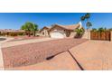 A wide shot of a tan single-story home and paved drive with desert landscaping and block fence at 15825 N 45Th St, Phoenix, AZ 85032