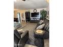 Spacious living room featuring comfortable seating, stylish decor, and large television for entertainment at 17823 N 99Th Dr, Sun City, AZ 85373