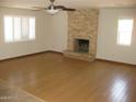 Living room featuring a stone fireplace, ceiling fan, and wood-look flooring at 27239 N 64Th Way, Scottsdale, AZ 85266