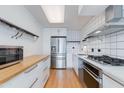 Modern kitchen with stainless steel appliances, white cabinets, and a wooden countertop breakfast bar at 4808 N 24Th St # 806, Phoenix, AZ 85016