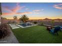 Backyard with a beautiful pool, desert landscaping, and cozy seating area with a fire pit at sunset at 537 E Balao Dr, Phoenix, AZ 85085