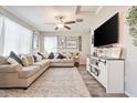 Bright living room boasts a large sectional sofa, ceiling fan, and a stylish entertainment center at 8043 W Albeniz Pl, Phoenix, AZ 85043