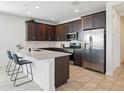 Modern kitchen with stainless steel appliances, dark cabinets, and a breakfast bar at 9310 W Atlantis Way, Tolleson, AZ 85353