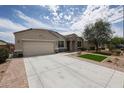 A beautiful home exterior is featured with an extended driveway, lush lawn, and stone accents at 30213 W Fairmount Ave, Buckeye, AZ 85396