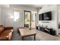 Bright living room featuring a leather sofa, hardwood floors, and a sliding glass door to the balcony at 7300 E Earll Dr # 1022, Scottsdale, AZ 85251