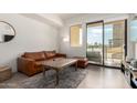 Cozy living room showcasing a leather sofa, wood floors, and natural light from the balcony at 7300 E Earll Dr # 1022, Scottsdale, AZ 85251