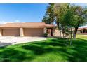 Home's exterior showcases a beautiful lawn, mature trees, and a driveway leading to the attached garages at 945 N Pasadena -- # 62, Mesa, AZ 85201