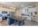 Bright kitchen features stainless steel appliances, tiled floors, white cabinetry, and a center island with bar seating at 9642 E Irwin Ave, Mesa, AZ 85209