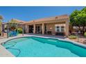 Backyard with sparkling pool, covered patio, seating area, lush landscaping, and a blue sky at 9642 E Irwin Ave, Mesa, AZ 85209
