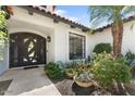 A home's inviting entry with a custom wrought iron door, tiled walkway, and vibrant potted plants at 3117 E Maryland Ave, Phoenix, AZ 85016