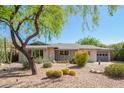 Charming home featuring a desert landscaped front yard with mature trees and an attached two-car garage at 8313 E Camelback Rd, Scottsdale, AZ 85251