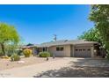 Single-story home with desert landscaping, mature trees, a two-car garage, and a paved driveway at 8313 E Camelback Rd, Scottsdale, AZ 85251