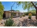 Attractive desert landscaping frames this home, highlighting the mature trees and large windows at 8313 E Camelback Rd, Scottsdale, AZ 85251