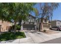Gray home featuring a well-maintained lawn, a driveway, and a two-car garage at 13434 W Rovey Ave, Litchfield Park, AZ 85340