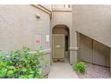 Front entrance with an arched entryway and a secure gate, and green foliage at 15225 N 100Th St # 1209, Scottsdale, AZ 85260