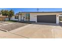 Modern single-story home with a gray garage door, concrete driveway, and desert landscaping at 1920 N Cavalier Dr, Tempe, AZ 85288