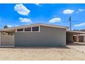 Side view of a single-story home featuring a carport and desert landscaping under a bright, sunny sky at 2325 E Delgado St, Phoenix, AZ 85022