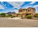 View of the front of a large two story tan colored home with a 3 car garage and desert landscaping at 26926 N 55Th Ln, Phoenix, AZ 85083