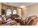 Comfortable living room featuring leather sofas, tile floors, and large windows, perfect for relaxation and entertaining at 26926 N 55Th Ln, Phoenix, AZ 85083