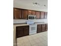 Bright kitchen featuring dark wood cabinets, white appliances and tile flooring under track lighting at 3454 E Bellerive Pl, Chandler, AZ 85249