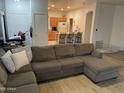 Open-concept living room with a gray sectional sofa that leads to a kitchen with barstool seating at 44899 W Portabello Rd, Maricopa, AZ 85139