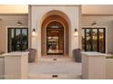 Elegant arched entryway with stone accents, flanked by stylish windows and planters, creating a welcoming entrance at 6633 E Horseshoe Rd, Paradise Valley, AZ 85253
