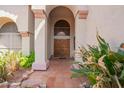 Inviting front entryway with a tiled landing, arched doorway and desert landscaping at 21483 N 65Th Ave, Glendale, AZ 85308