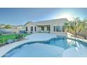 Beautiful backyard featuring a private pool, covered patio, palm trees, and lush green lawn at 329 S Marin Dr, Gilbert, AZ 85296