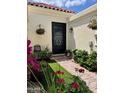 Close-up of front door with black decorative door, brick pathway, and colorful flowers at 3800 E Lincoln Dr # 37, Phoenix, AZ 85018