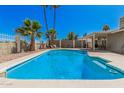 The backyard pool area offers a refreshing retreat, complete with lounge chairs, covered patio, and palm trees at 4305 N 101St Ave, Phoenix, AZ 85037