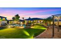Beautiful backyard with lush lawn, sparkling pool, fire pit, lounge seating, and evening sky at 4865 S Cylinder Way, Mesa, AZ 85212