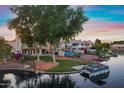 Waterfront backyard featuring a boat dock and boat, and a serene lake view with mature trees at 1267 E Chicago Cir, Chandler, AZ 85225