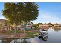 Waterfront backyard featuring a boat dock and boat, and a serene lake view with mature trees at 1267 E Chicago Cir, Chandler, AZ 85225