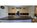 Kitchen with an island featuring a sink, granite countertops, light wood cabinets, and modern lighting fixtures at 15241 W Coolidge St, Goodyear, AZ 85395