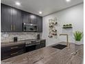 Modern kitchen features sleek black cabinetry with gold hardware, designer wine rack, and stone countertops at 5995 N 78Th St # 2078, Scottsdale, AZ 85250