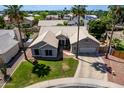 Beautiful aerial view of a home with a tile roof, lush lawn, desert landscaping, and mature palm trees at 6577 W Abraham Ln, Glendale, AZ 85308