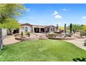 Expansive backyard featuring synthetic grass, desert plants, and a built-in patio area at 8703 E Nora St, Mesa, AZ 85207