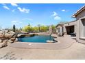 Inviting pool area showcasing desert landscaping, rock features, and outdoor lounge area at 8703 E Nora St, Mesa, AZ 85207