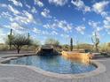 Backyard pool showcasing a rock waterfall and desert views under a blue sky at 8703 E Nora St, Mesa, AZ 85207