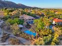 Aerial view of a home with a sparkling blue pool, mature landscaping, and mountain views at 12240 S Honah Lee Ct, Phoenix, AZ 85044
