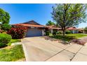 Well-maintained home featuring a gray garage door, vibrant flowering bushes, and a neatly kept lawn under a clear blue sky at 12954 W Blue Sky Dr, Sun City West, AZ 85375