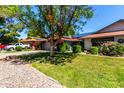 Inviting home with lush green lawn, blossoming flowers, and mature trees providing ample shade and curb appeal at 12954 W Blue Sky Dr, Sun City West, AZ 85375