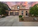 Two-story stucco home featuring a two-car garage, arched entry gate, and Southwestern architectural details at 13648 W Jesse Red Dr, Peoria, AZ 85383