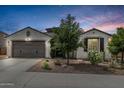 Charming single-story home featuring a two-car garage and desert landscaping at dusk at 21840 N 260Th Ln, Buckeye, AZ 85396