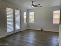 Bright living room with wood-look floors, ceiling fan, and access to the backyard through french doors at 6557 S Classic Way, Gilbert, AZ 85298