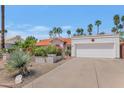 Home exterior with a two-car garage, mature landscaping, and a red tile roof under a blue sky at 8666 E Cheryl Dr, Scottsdale, AZ 85258