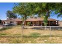 Charming single-story home featuring a chain-link fence, mature trees and a well-maintained lawn at 11422 W Hidalgo Ave, Tolleson, AZ 85353