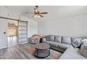 Bright living room featuring modern gray sectional sofa, stylish ceiling fan, and a decorative sliding barn door at 16258 N 138Th Ave, Surprise, AZ 85374