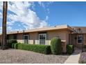 Tan home with green shutters and trimmed bushes, offering privacy and curb appeal at 17238 N 107Th Ave, Sun City, AZ 85373